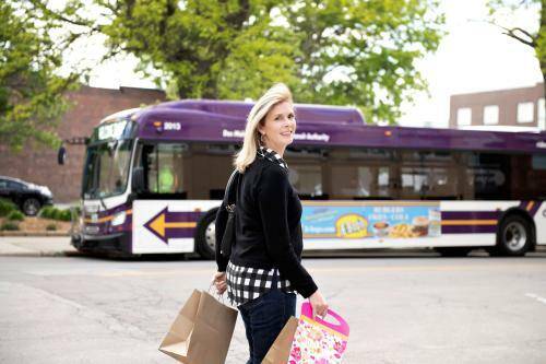 Woman enjoying shopping in the East Village of Des Moines with a DART bus in the background