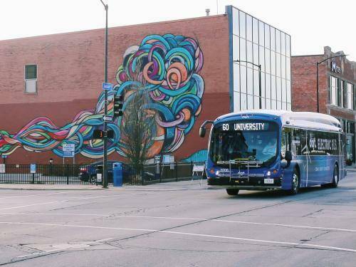electric bus with mural in background on the road