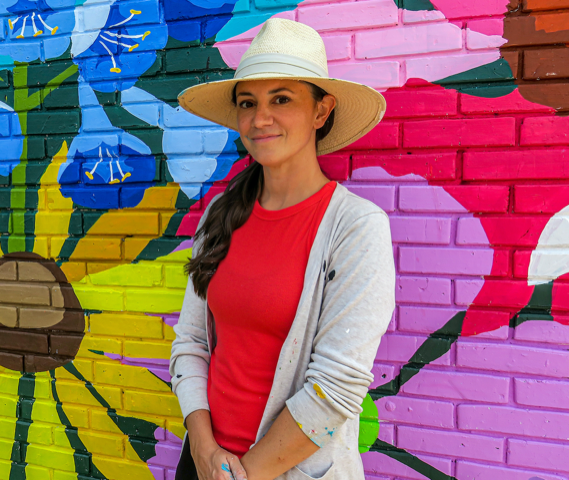 Photo of female artist with mural in background 